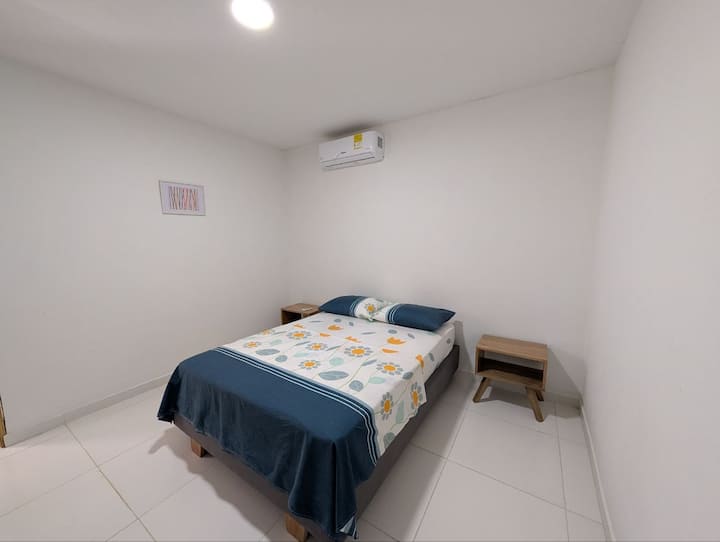 Værelse med dobbeltseng, aircondition, ventilator, sengeborde og plads til at organisere dit tøj.