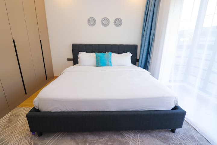 חדר שינה ראשי מרווח עם מיטת קינג-סייז, נוף לעיר, תריסי האפלה, מצעים נקיים ושפע של מקום אחסון, מנוחה בסטייל ובנוחות.