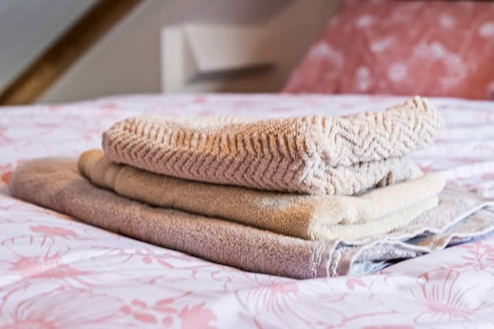 „Svježe složeni ručnici na krevetu, spremni za dolazak gostiju.”