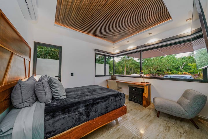 Recámara moderna y luminosa con vistas al jardín, espacio de trabajo y asientos acogedores