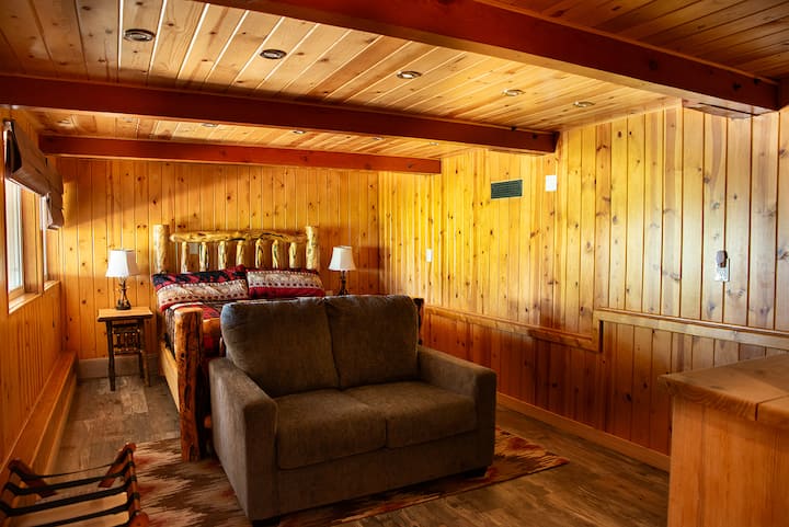 Სოფლის დედოფლის საძინებელი, რომელშიც არის შესასვლელი ჩარჩოიანი საწოლი, ხის მყუდრო პანელებით მოპირკეთებული კედლები და კომფორტული მოსასვენებელი სივრცე თავგადასავლების შემდეგ განტვირთვისთვის.