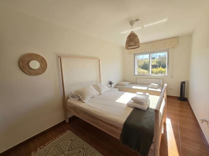 Bedroom with a double bed and a twin bed, designed for maximum comfort. Enjoy spectacular views of the garden and the mountains right from your window. A bright, quiet, and cozy retreat, ideal for disconnecting and resting.