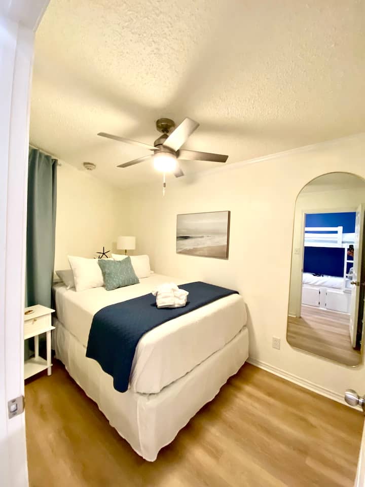 El dormitorio cuenta con un colchón nuevo con una almohadilla protectora y sábanas frescas, complementado con un ventilador de techo para mantenerte fresco por la noche y muebles modernos para una estancia cómoda.
