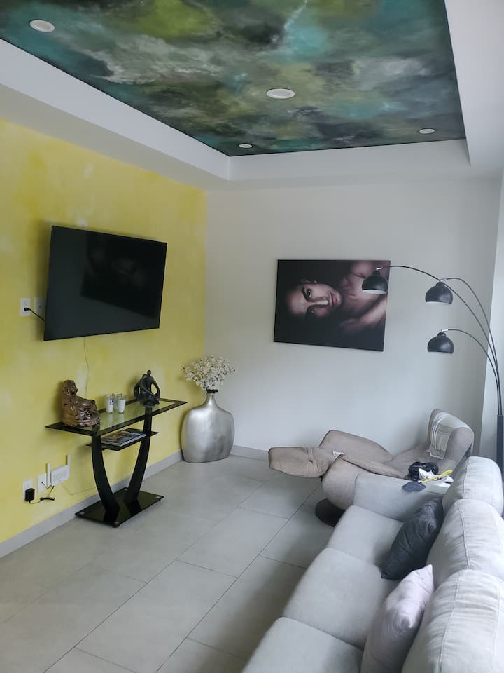 Svetlá pohodlná obývacia izba s rozkladacou pohovkou veľkosti Queen, elektrickým sklápacím kreslom, 55-palcovou SMART TV a klimatizáciou.  