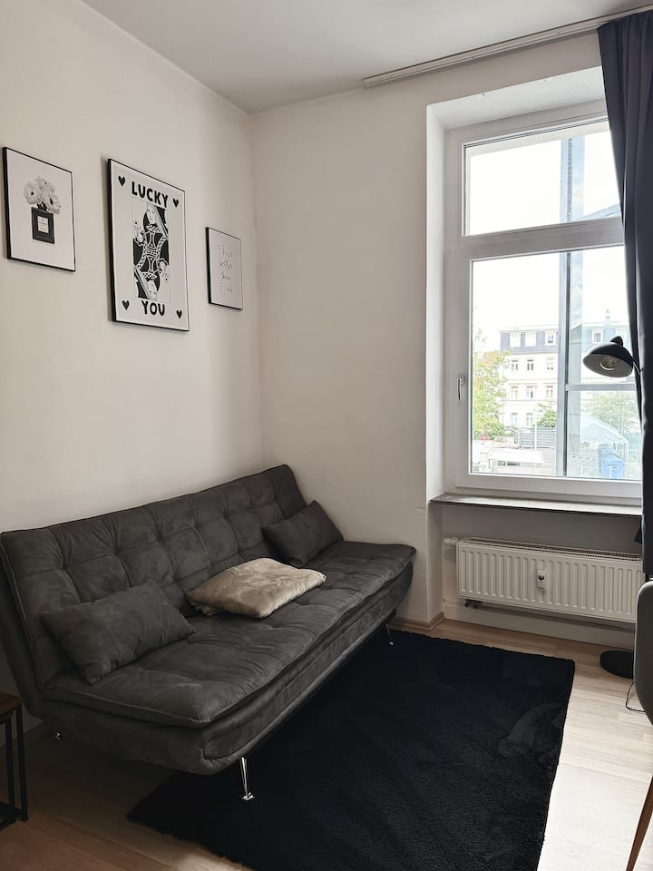 Offener Wohnraum mit komfortablem Schlafsofa und stylishem Teppich – ideal zum Entspannen, Plaudern oder Lesen. Das Schlafsofa einfach ausklappen und entspannen mit direktem Blick auf 55-Zoll TV.