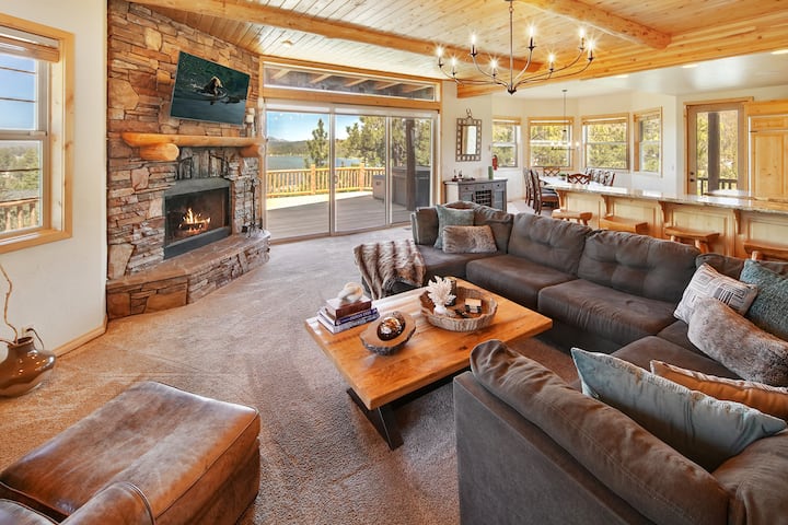 Big lake view from living room with comfy sectional and leather chair opens to kitchen and large deck overlooking Lake Big Bear