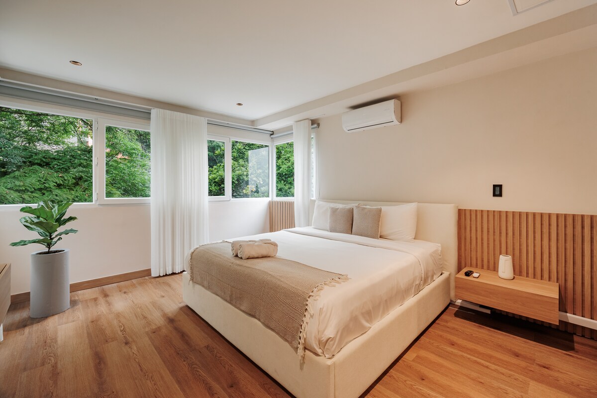 Un dormitorio bellamente diseñado con una cama tamaño king, baño privado y un espacioso vestidor. Luminoso y elegantemente amueblado, ofrece una comodidad excepcional y un ambiente sereno para una estancia lujosa.