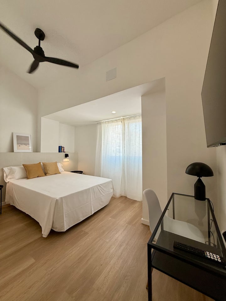 DORMITORIO 1: Cama doble con BAÑO 2 completo en-suite, zona de escritorio, TV Smart, ventilador de techo, aire acondicionado tipo split, y ventana con persiana enrollable y cortina liviana para mayor privacidad.