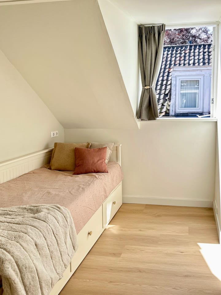 غرفة نوم مضيئة ومدمجة مع سرير متعدد الاستخدامات يعمل كسرير فردي أو يتكشف ليصبح سريرًا مزدوجًا واسعًا.