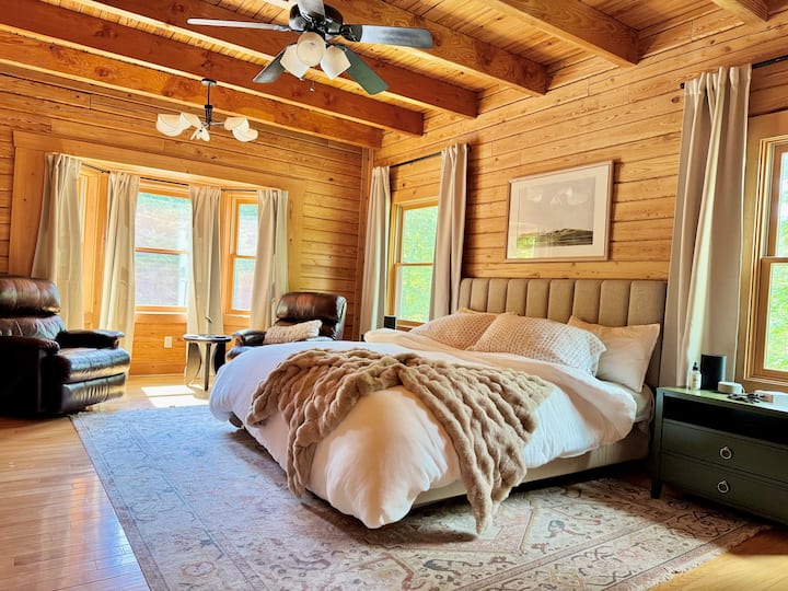 Slaapkamer op de begane grond met aangrenzende badkamer, leren ligstoelen, smart-tv, plafondventilator, dressoir 