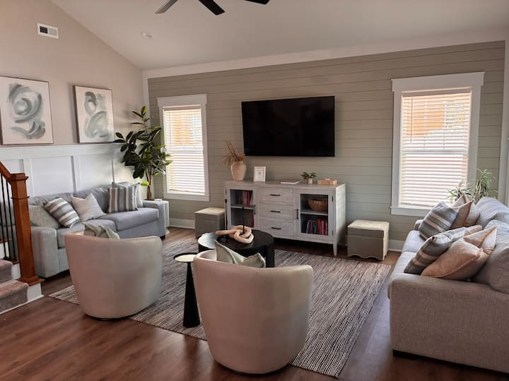 Bright, stylish lounge with shiplap wall, big TV, and seating for all