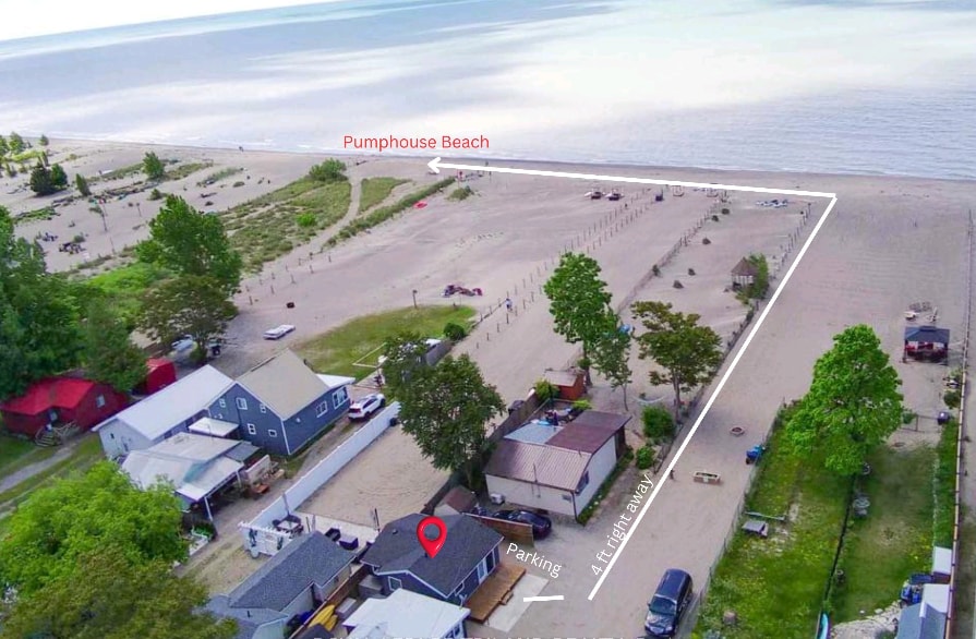 An aerial view of the surrounding area shows the proximity to Pumphouse Beach, with a sandy shoreline stretching beside the water. Several trees and nearby residences are visible, along with a designated parking area marked for convenience.