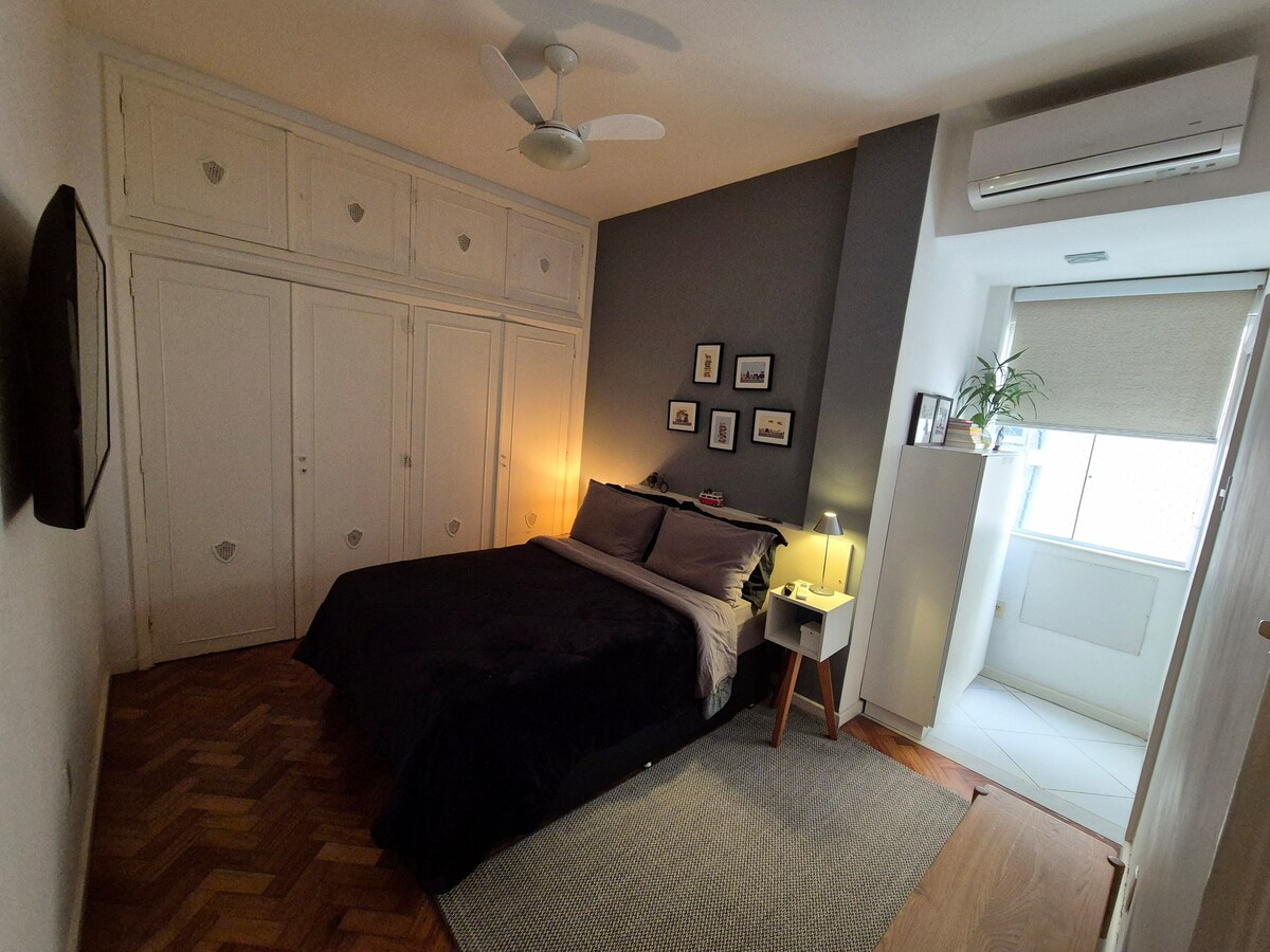 غرفة نوم داخلية مع سرير مزدوج وتلفزيون ومروحة ومكيف هواء منفصل. 