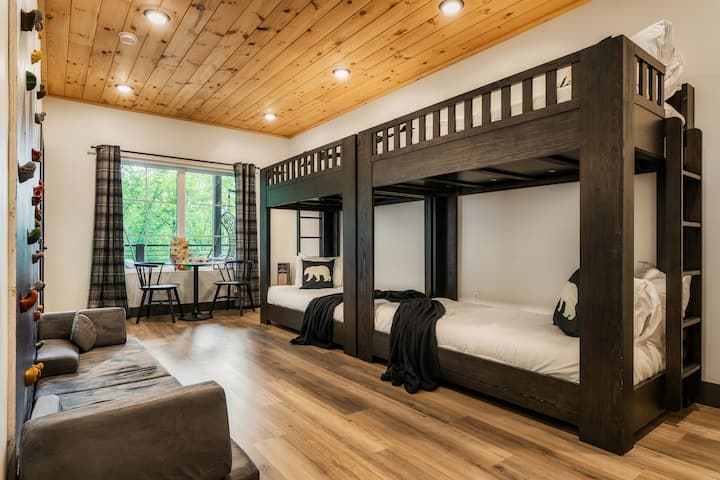 La chambre superposée et l'aire de jeu intérieure idéales pour les enfants! Comprend quatre lits superposés intégrés confortables, un canapé bas et un mur d'escalade intérieur. Comprend une petite table d'activités et une fenêtre lumineuse donnant sur les arbres.
