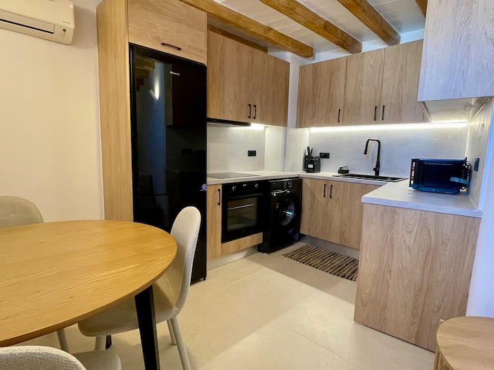 מטבח בית הארחה מאובזר עם מכשירים מודרניים, פינת אוכל וגווני עץ אלגנטיים – חלק מהאחוזה הפרטית Villa Idro