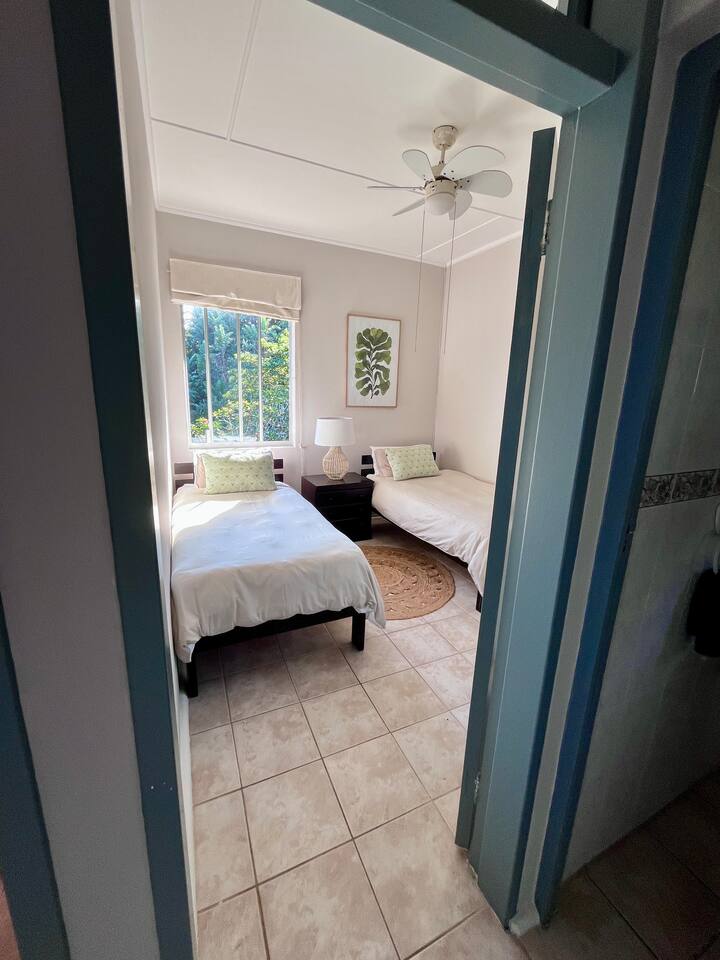 ห้องนอน 3 มีเตียงเดี่ยวที่สะดวกสบาย 2 หลัง เหมาะสำหรับเด็กหรือเพื่อน ๆ เข้าพักร่วมกัน ที่พักสว่างและโปร่งโล่งพร้อมวิวสวน สีโทนอ่อนๆ โต๊ะข้างเตียงพร้อมโคมไฟ พัดลมเพดาน และที่เก็บของในตัว เพื่อการเข้าพักที่ผ่อนคลายและสบายใจ