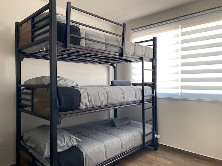 Ფუნქციური და ლამაზი ოთახი სამადგილიანი ლითონის ორსართულიანი საწოლით, იდეალურია დიდი ჯგუფებისთვის ან ბავშვებით სავსე ოჯახებისთვის.