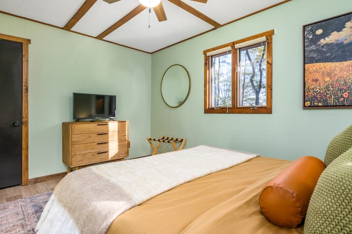 غرفة نوم أنيقة ثانية في الطابق السفلي مع أثاث متميز وإطلالات هادئة على الغابة. 