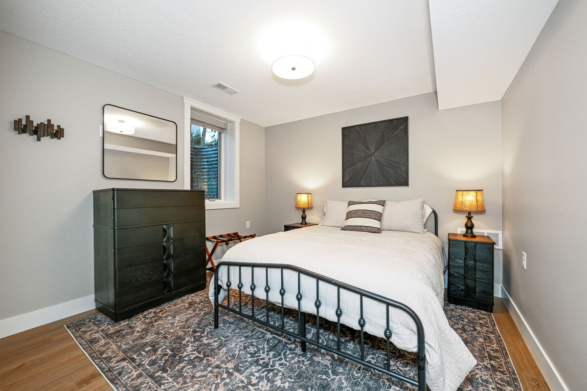 ห้องนอนคู่ทวินเลคชั้นล่าง ห้องนอน 1 ใน 2 ห้องที่ชั้นล่าง  เตียงควีนไซส์อยู่ติดกับห้องน้ำ  ตะขอติดผนังและที่วางกระเป๋าเดินทาง