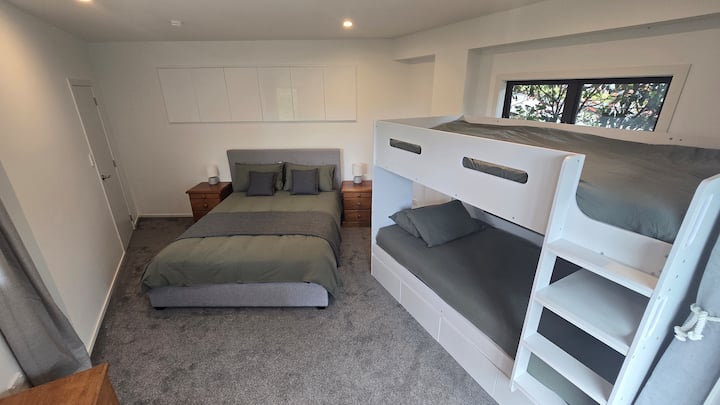 3e chambre au rez-de-chaussée avec lit double et lits superposés simples.  Accès à la salle de jeux et à la petite terrasse.  Téléviseur dans la salle de jeux attenante.