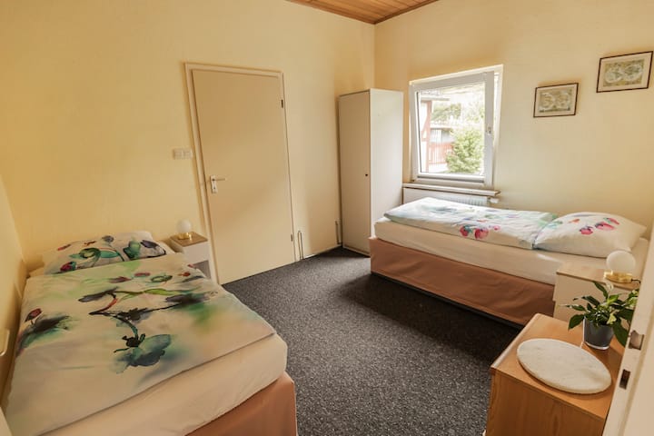 Cómoda habitación con dos camas individuales, mesitas de noche con lámparas y amplio espacio de almacenamiento. Una hermosa vista al jardín lo hace ideal para niños o amigos que viajan juntos. Con acceso al baño.