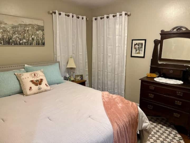 Queen bed with new mattress and soft linens - Blackout curtains + cellular blinds - Luggage rack - Antique dresser - Nightstand - Lamp - Child-sized play nook with whimsical charm - Jewelry box + tree - Thoughtful accents - Hardwood floors - Area rug