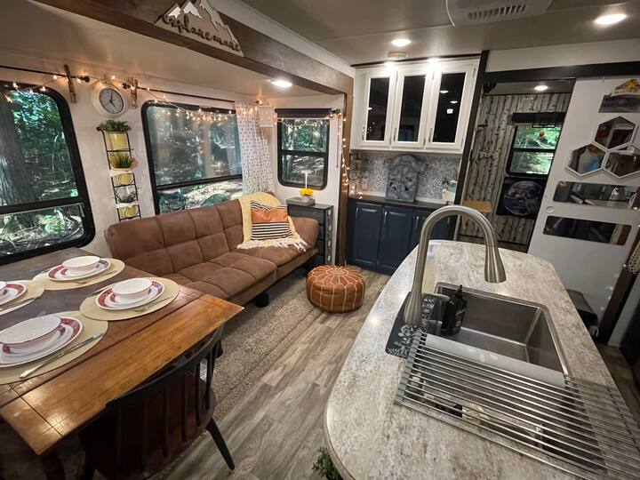 Stol za 4 osobe, jedna osoba sjedi na kauču. 