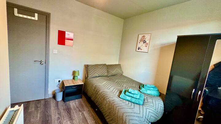 Chumba cha kulala cha starehe kilicho na kitanda cha watu wawili, mashuka safi ya kitanda, uhifadhi wa kutosha wa nguo, viango, mfumo wa kupasha joto, pasi na vivuli vyenye giza chumbani kwa ajili ya kulala usiku kwa utulivu. Imebuniwa ili kutoa kila kitu unachohitaji kwa ajili ya ukaaji wa kupumzika na rahisi.