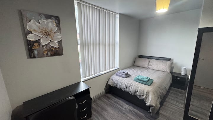 Chumba cha kulala cha starehe kilicho na kitanda cha watu wawili, mashuka safi ya kitanda, uhifadhi wa kutosha wa nguo, viango, joto, pasi, vivuli vya giza vya chumba, pamoja na meza na kiti, vinavyofaa kwa kazi au masomo. Iliyoundwa kwa ajili ya ukaaji wa kupumzika na rahisi.