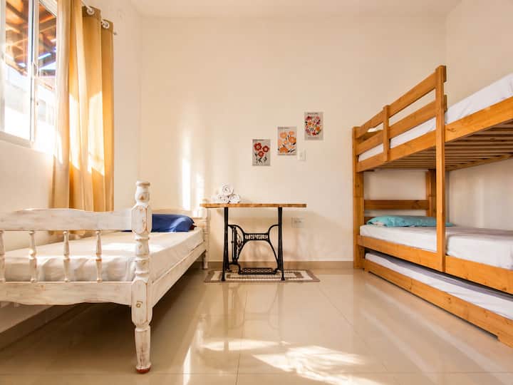 Quarto térreo e espaçoso, com uma cama de solteiro e uma treliche, ventilador de teto, guarda-roupa e tela mosquiteira. Conta com toalhas de banho e a roupa de cama básica (travesseiros, fronhas e lençóis). Recomendamos trazer cobertores.