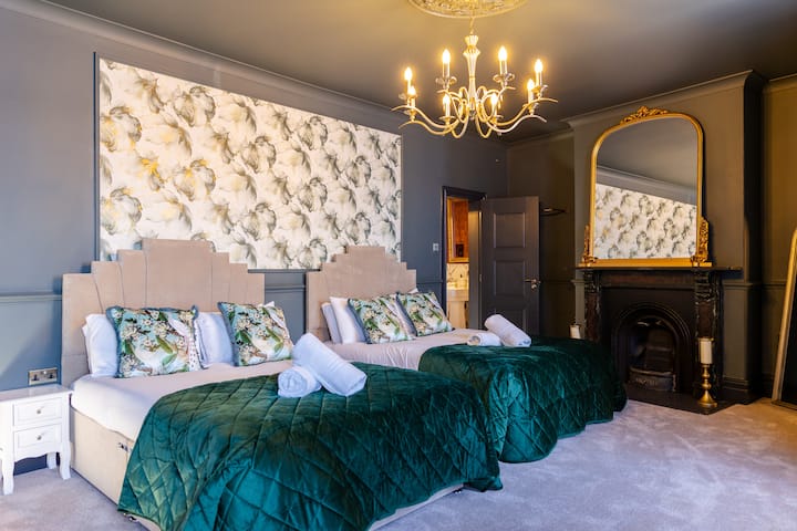 Голема и пространа спална соба со два луксузни брачни кревета, огромно огледало на подот, масичка за облекување и елегантно огниште. Преполна со карактер и стилски детали, оваа соба нуди удобност и шарм во еднаква мера.