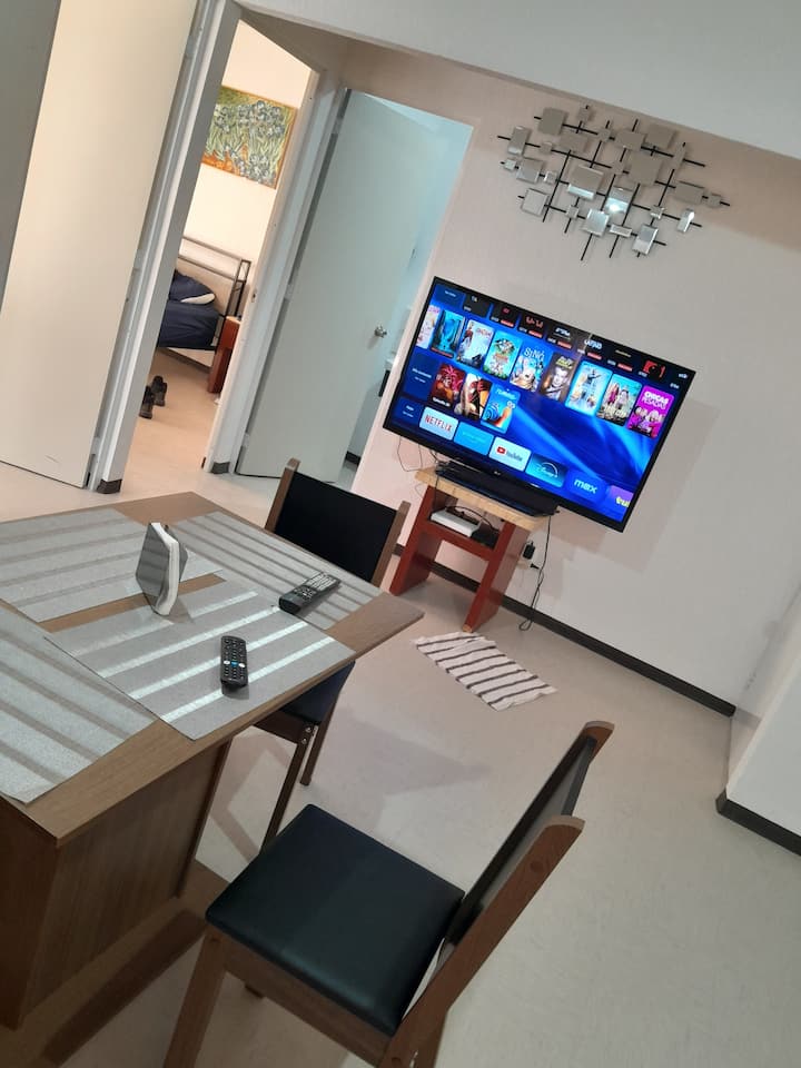 "غرفة معيشة مريحة بها منطقة طعام متكاملة لأربعة أشخاص." مثالي للاستمتاع بمشاهدة فيلم على التلفزيون الذكي بشاشة مسطحة أو للعمل في بيئة هادئة مع توفر شبكة واي فاي.”