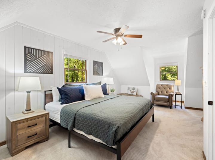 Priestranná spálňa s manželskou posteľou, dvoma sedacími kútmi (gauč a stolička) a televízorom, na poschodí hlavného domu 