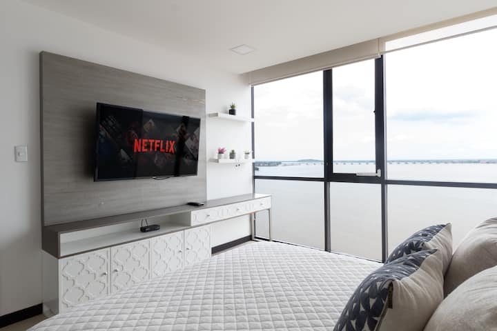 Habitación moderna con hermosa vista al río, cama de 2 plazas y media, cortinas blackout, walk-in-closet, baño y Smart TV con acceso a Netflix, Disney+ y canales nacionales e internacionales.