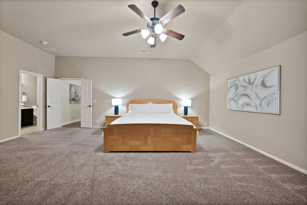 This king-size master suite includes an ensuite bathroom and a balcony overlooking the pool and backyard oasis.