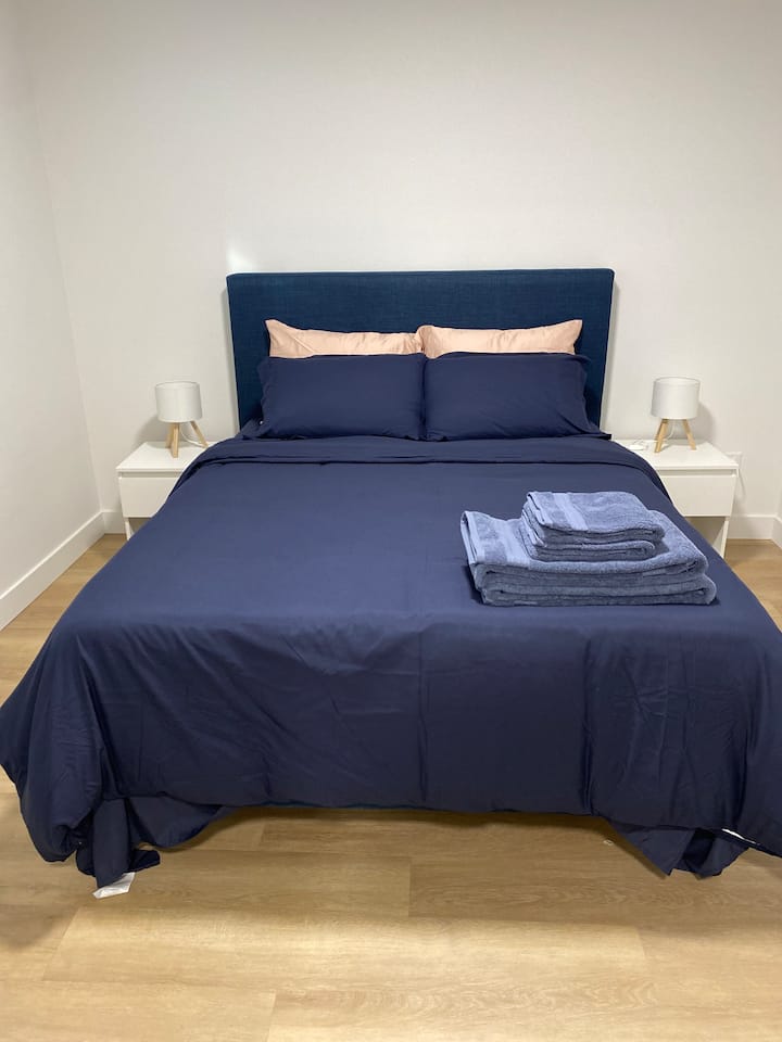 Útulná spálňa s prémiovou čerstvou posteľnou bielizňou, nočnými stolíkmi a lampičkami na oboch stranách postele, ktoré poskytujú jednoduchý prístup a pohodlie pre každého hosťa