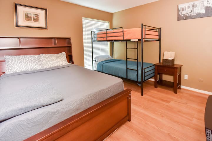 Este dormitorio excepcionalmente grande ofrece una disposición versátil para dormir, con una cama tamaño queen para adultos, una litera incorporada para niños y una cómoda cama nido para alojar a huéspedes adicionales.