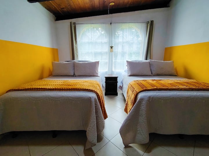 Chambre secondaire avec deux lits doubles, située au deuxième niveau.