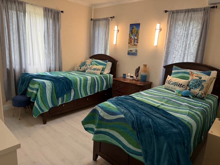 Perfecta para amigos, hermanos o niños, esta habitación luminosa y acogedora cuenta con dos cómodas camas individuales, una televisión inteligente, aire acondicionado y un clóset. La decoración costera y la suave luz natural crean un refugio relajante después de un día explorando Barbados.