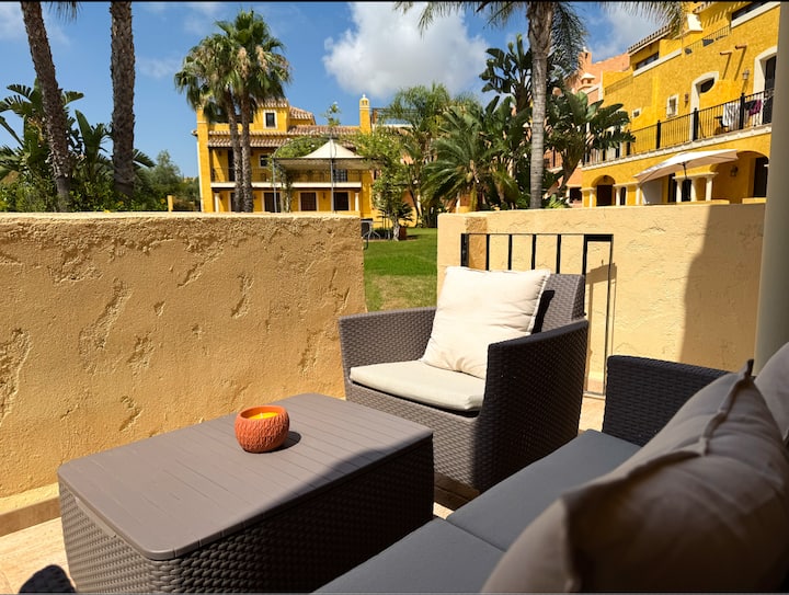 Desayuna en paz en la terraza con vistas al campo de prácticas y palmeras.