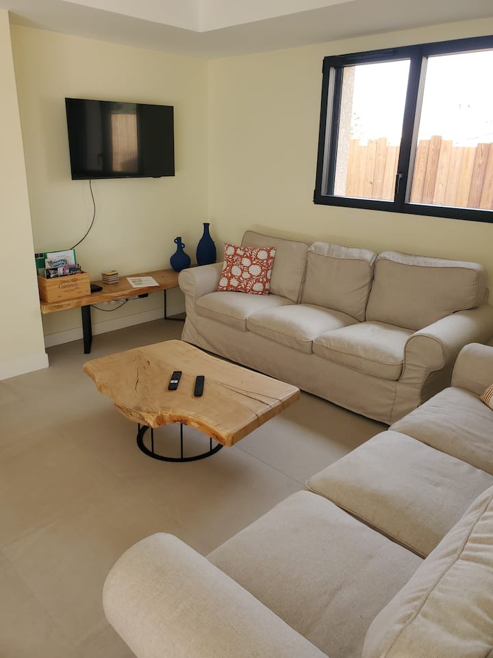 голема дневна соба со два големи каучи, паметен телевизор, кабелски приклучоци, клима уред 