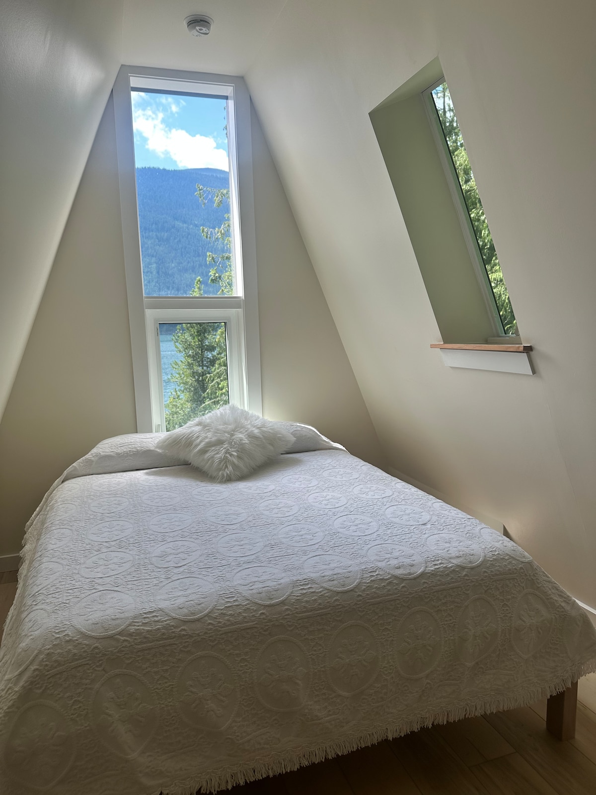 Lit Queen avec une belle vue sur la forêt de cèdres à travers le puits de lumière et une belle vue sur le lac et les montagnes depuis la fenêtre au-dessus.