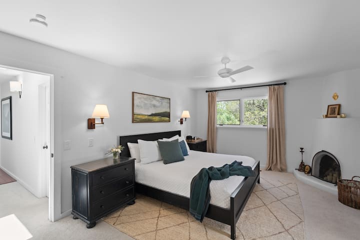Dormitorio moderno y sencillo con una cama tamaño king. La chimenea no funciona.