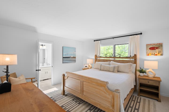 Una cama tamaño king, almacenamiento, ventana con cortinas opacas y luz natural: un dormitorio acogedor y sencillo con todo lo que necesitas.