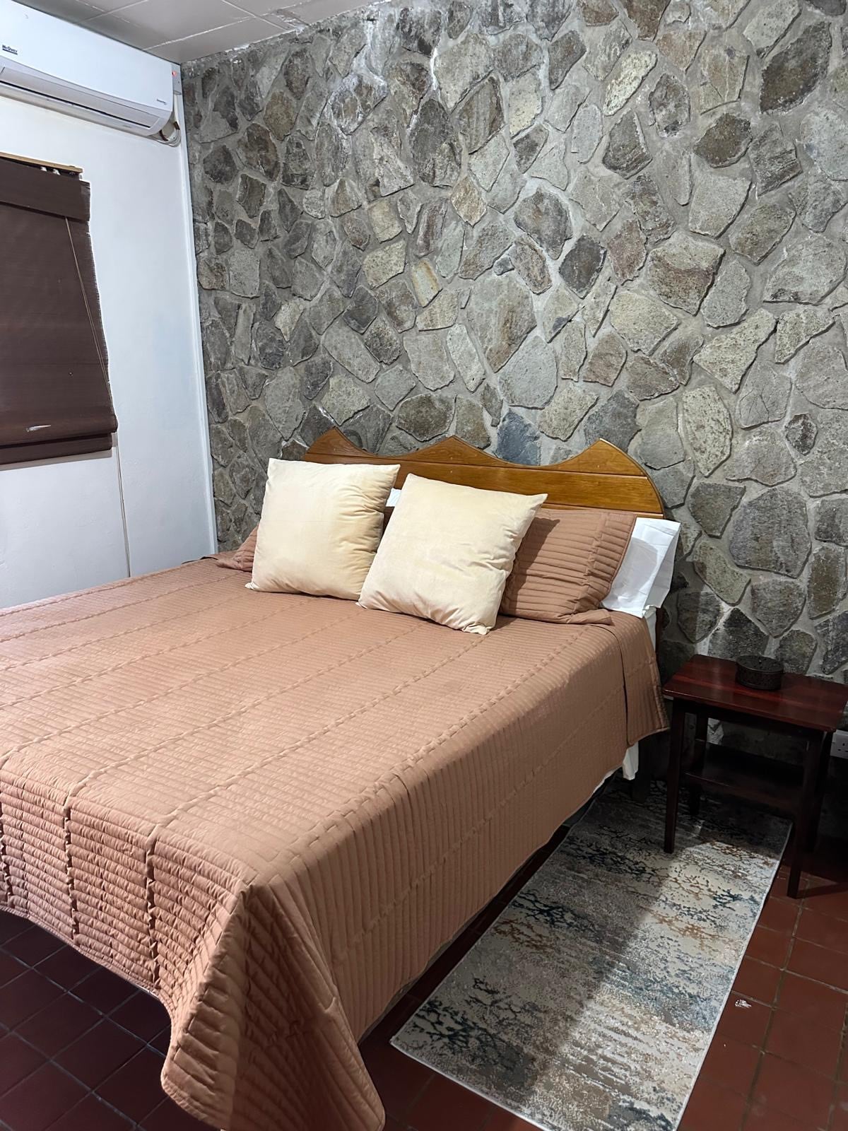 Kingsize bed omringd door natuursteen en grote hardhouten kasten. Ramen kunnen worden geopend voor natuurlijke luchtstroom als airco niet nodig is. 