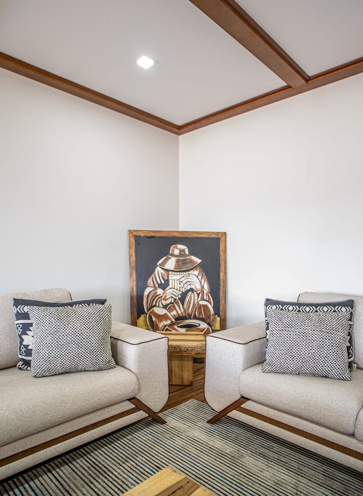 Დეკორატიული კუთხე ინდივიდუალური სავარძლებით, რბილი ბალიშებითა და ეთნიკური ხელოვნებით. Მყუდრო სივრცე წასაკითხად, დასასვენებლად ან მშვიდი საუბრისთვის.