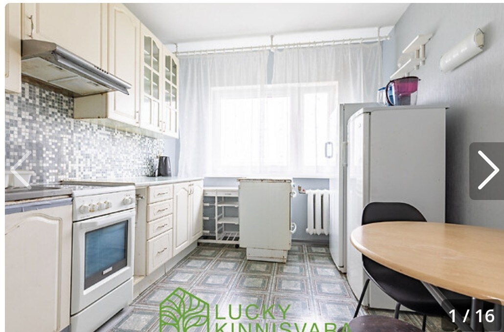 A kitchen area features white cabinetry and a tile backsplash with a mosaic pattern. A round table is paired with black chairs, while large windows allow natural light to fill the space. Kitchen appliances, including a stove and refrigerator, are present, contributing to functionality.