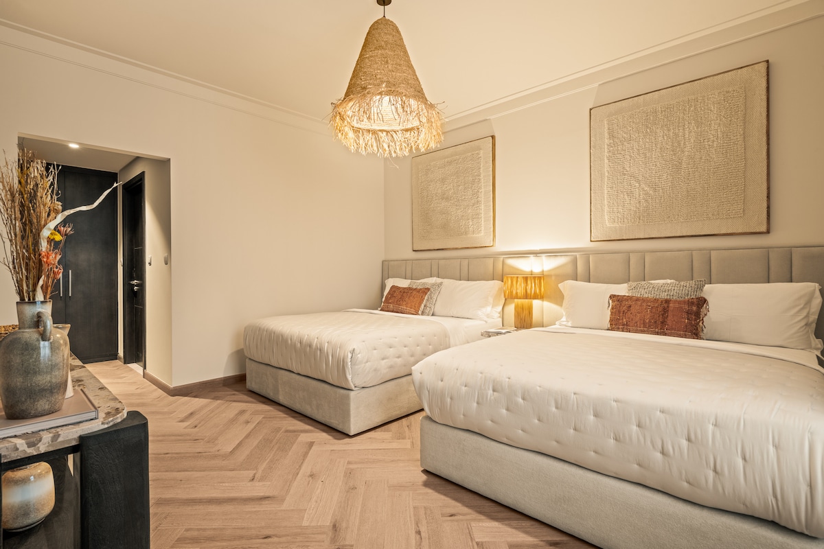 Táto priestranná a elegantne navrhnutá spálňa má dve luxusné manželské postele, teplé neutrálne tóny a mäkké osvetlenie pre relaxačnú atmosféru. Ideálna pre rodiny alebo skupiny, izba ponúka pohodlie, komfort a pokojný spánok.