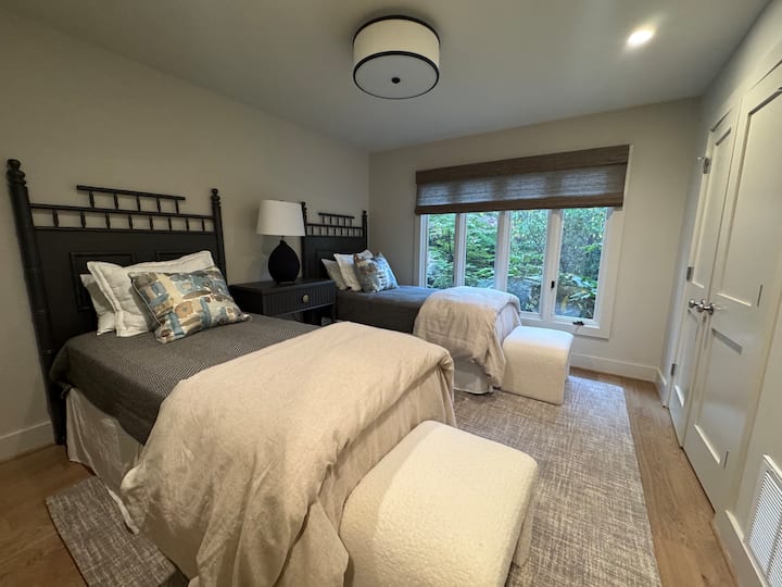 חדר שינה מחוץ לחלל הראשי בקומה הראשית עם שתי מיטות יחיד וארון עם חדר רחצה ממש מחוץ לדלת.