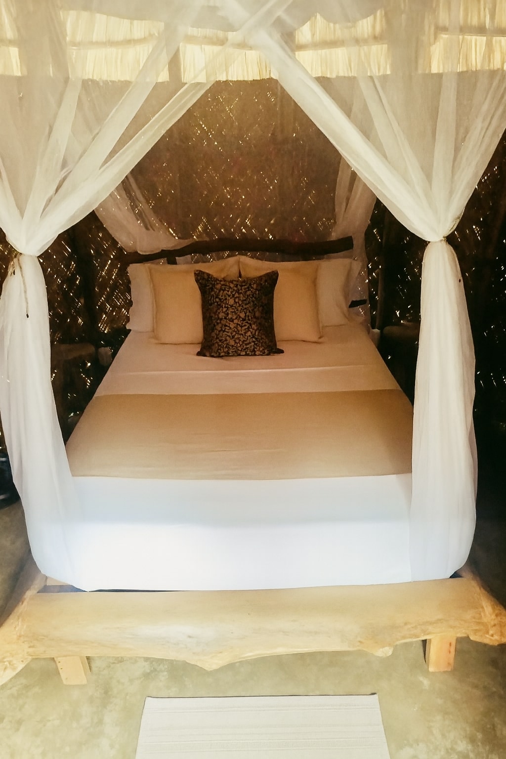 เตียงคู่สบายๆ พร้อมผ้าปูที่นอนนุ่มและมุ้งกันยุงสุดโรแมนติก — เหมาะสำหรับการพักผ่อนยามค่ำคืนภายใต้แสงธรรมชาติ